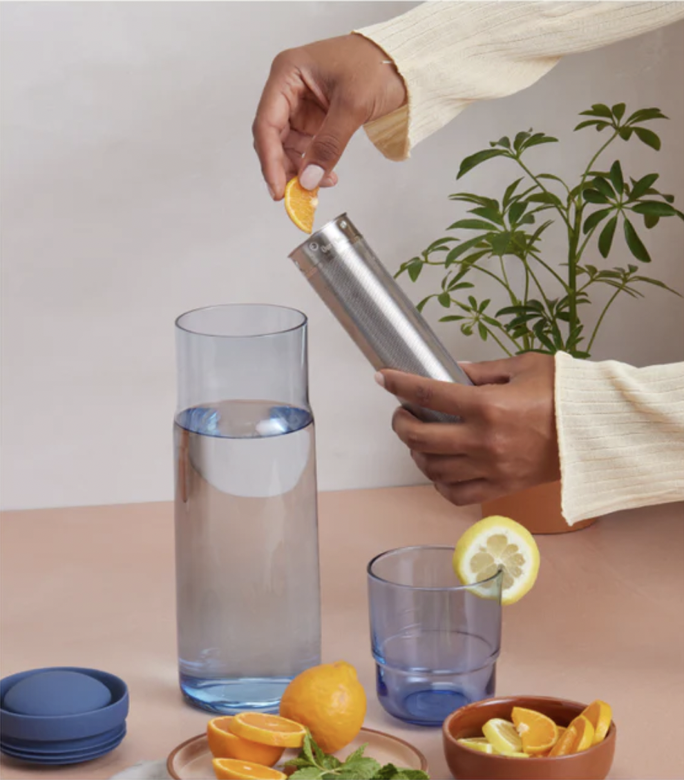 a person putting citrus fruit into the carafe&#x27;s infuser