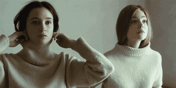 Two girls put on matching turtleneck sweaters