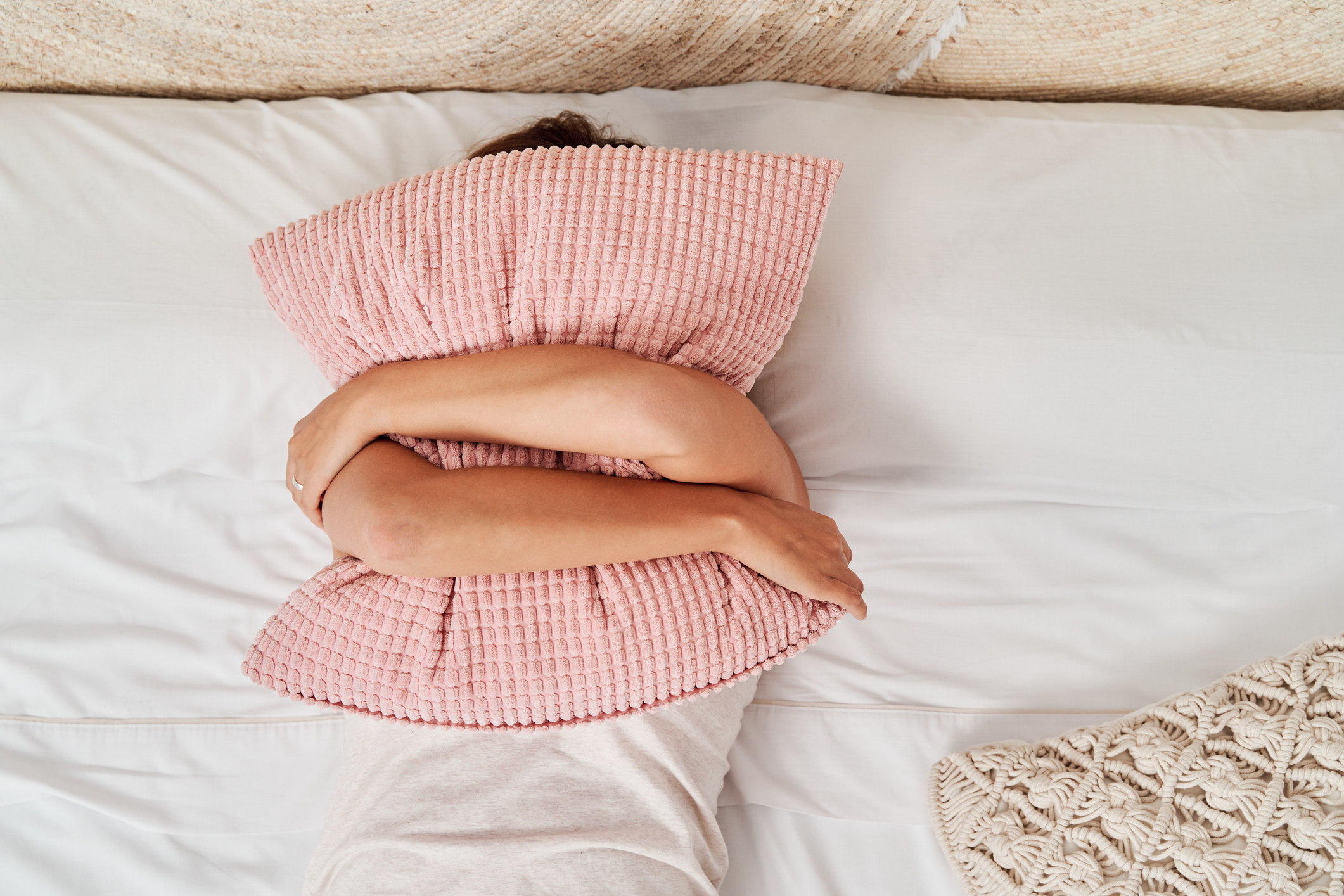 person hugging a pillow in bed