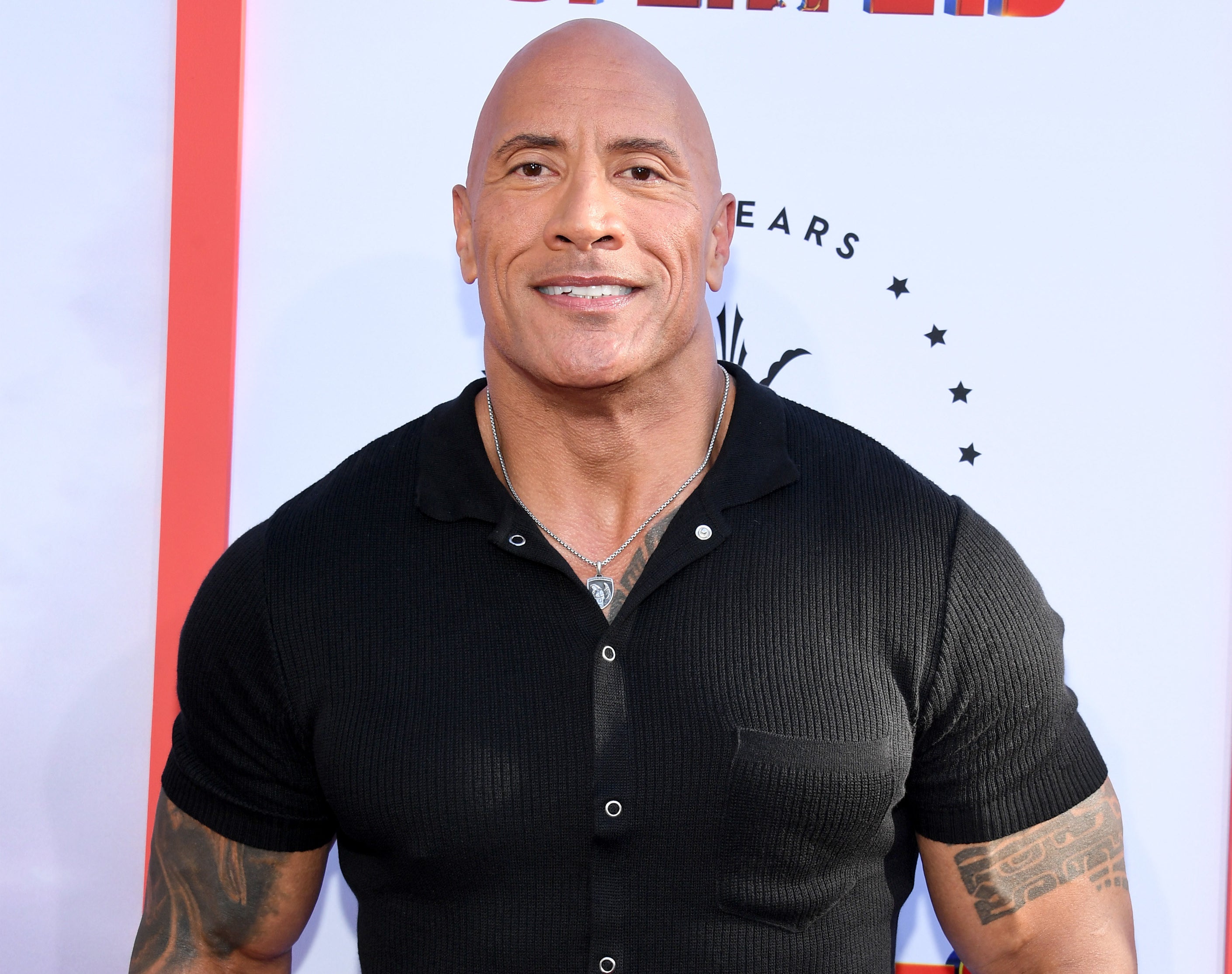 Dwayne in a short-sleeved shirt showing his biceps and tattoos
