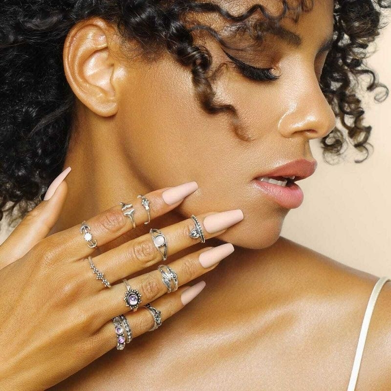 A person wearing multiple rings with a nude manicure