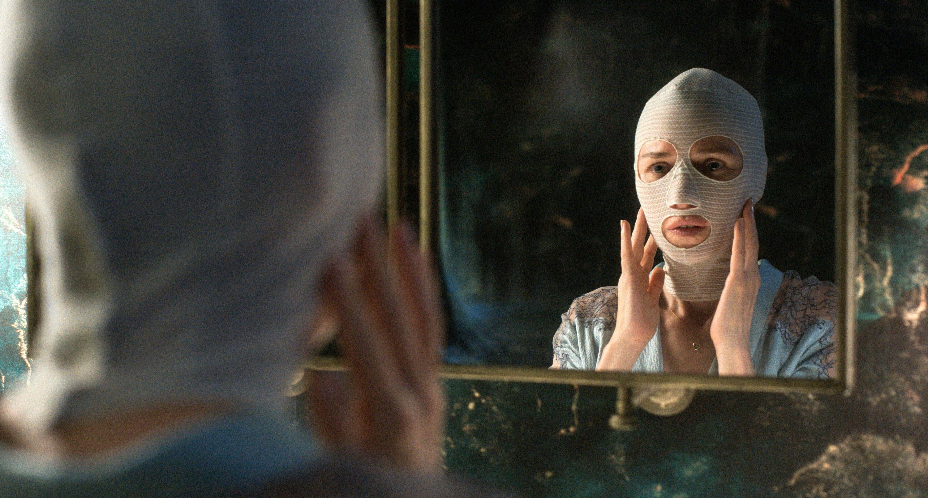 A woman rebuilding her face examines her mask in the mirror in “Goodnight Mommy”
