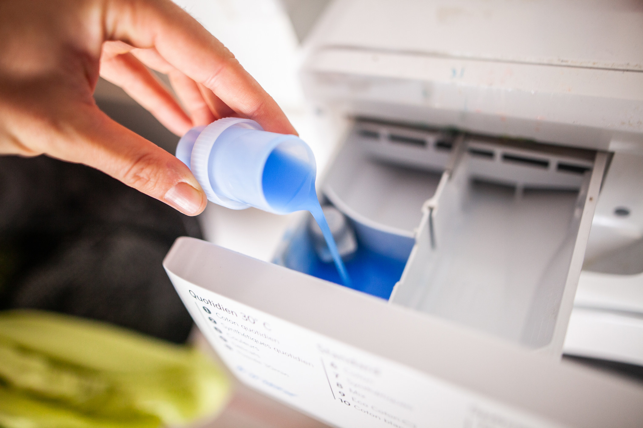 A hand pouring washing detergent