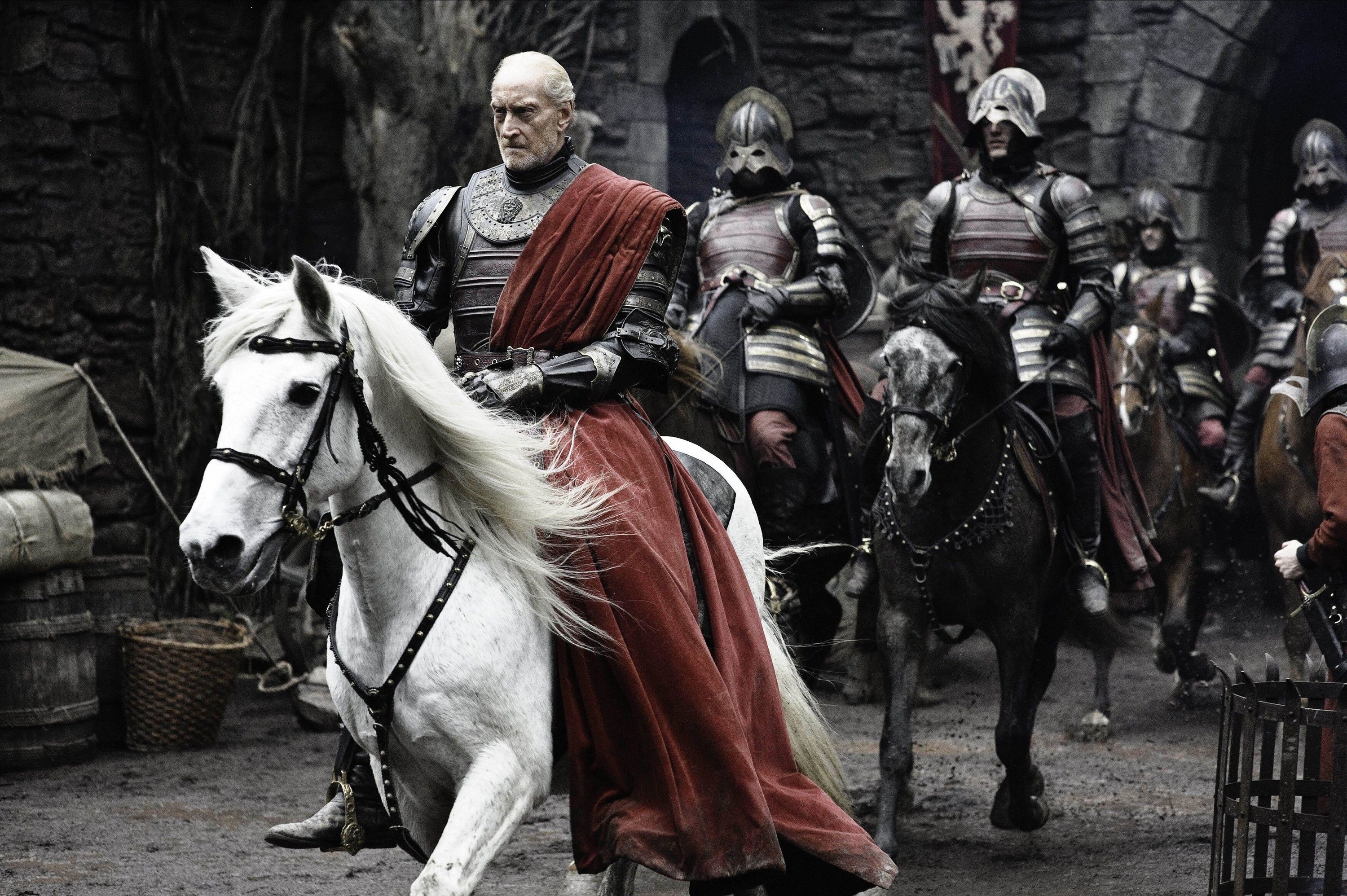 A man with a red cape and armor rides in on a white horse.