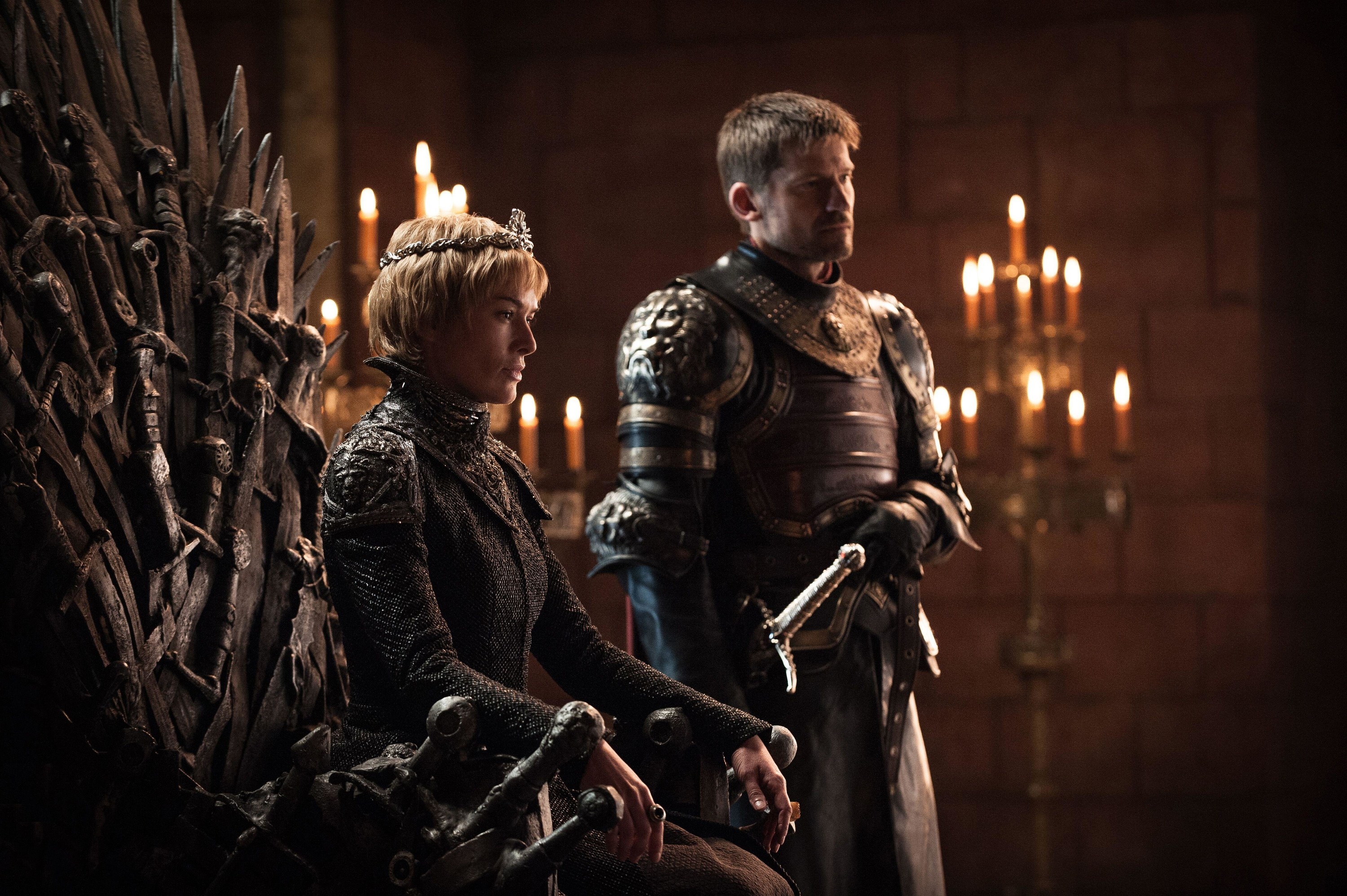 A blonde haired woman sits atop the Iron Throne next to her brother