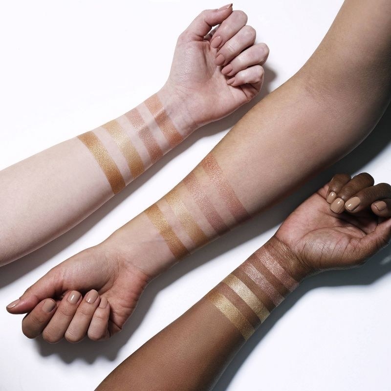 A set of highlighter swatched on three different skin tones