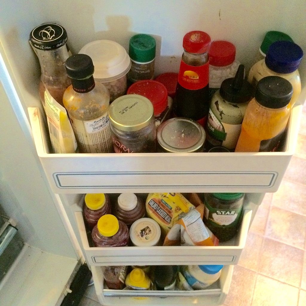 An overcrowded fridge door with sauces