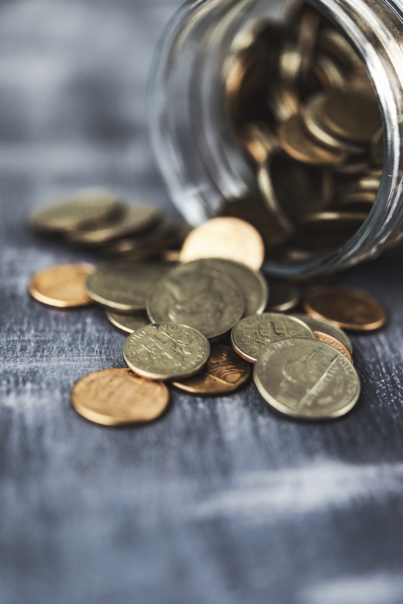 Loose change spilling from a savings jar of money