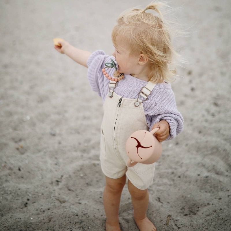 Little girl holding snack cup on sand