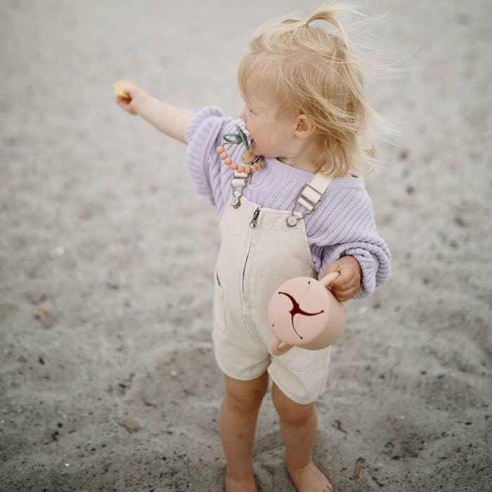 小女孩拿着零食杯在沙地上