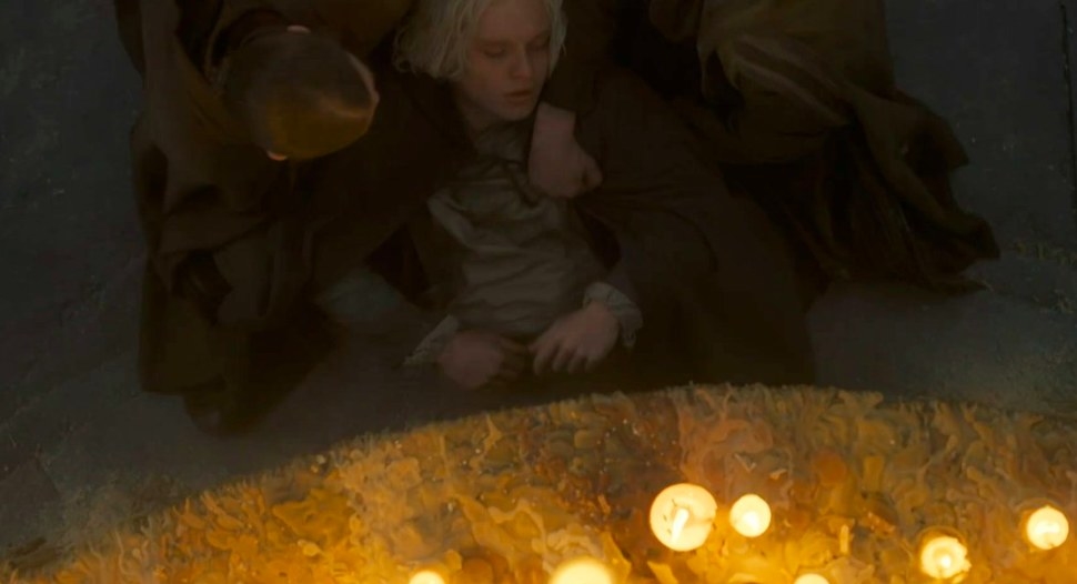 Aegon is pulled out from under a table lit by candles by the Kingsguard twins
