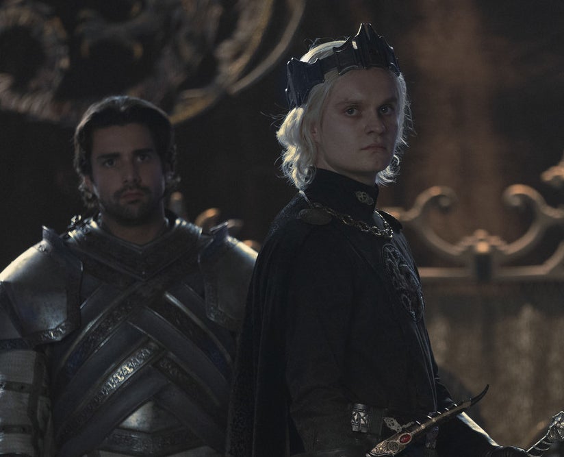 Aegon wears a crown and stands in front of Criston Cole