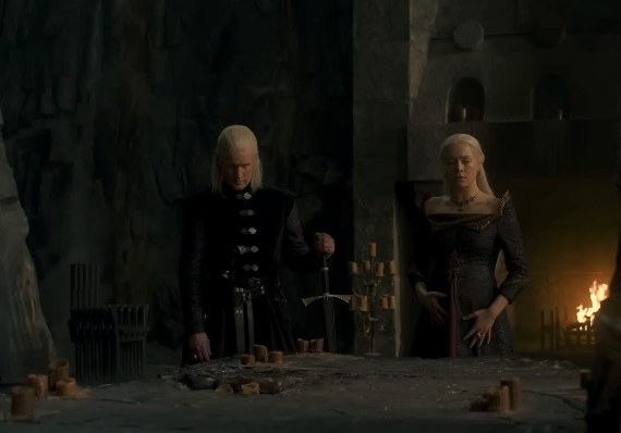 Rhaenyra looks shocked and Daemon seems unsurprised; they stand by the painted table