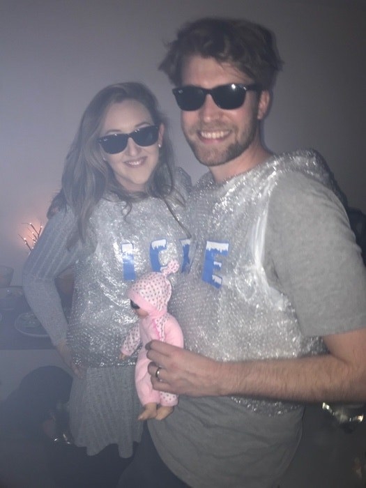 Two people in dark sunglasses wearing silvery &quot;Ice&quot; shirts and holding a baby doll