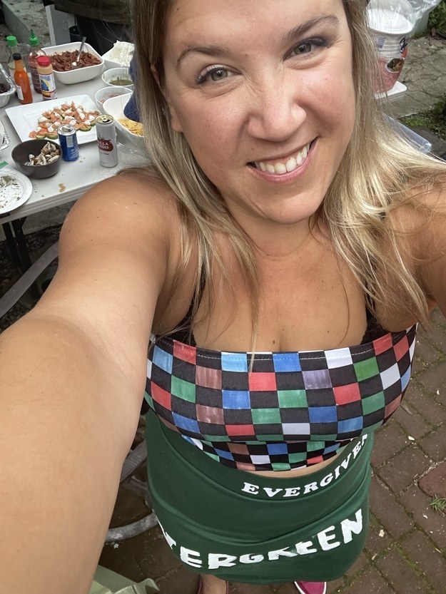 A smiling person waring a multicolored checkered &quot;Evergreen&quot; apron