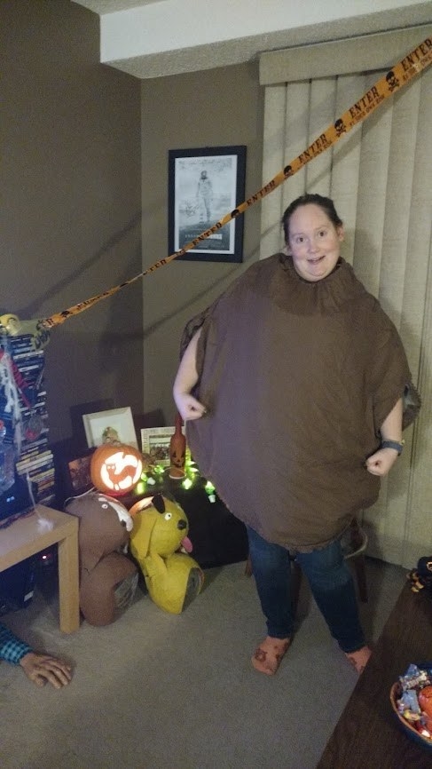 A person wearing a large brown, round sack with holes for their arms