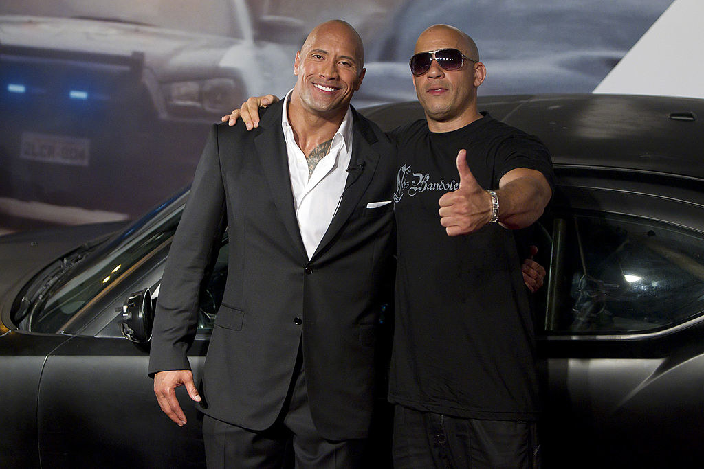 Vin Diesel wears a dark T-shirt and Dwayne Johnson wears a dark suit