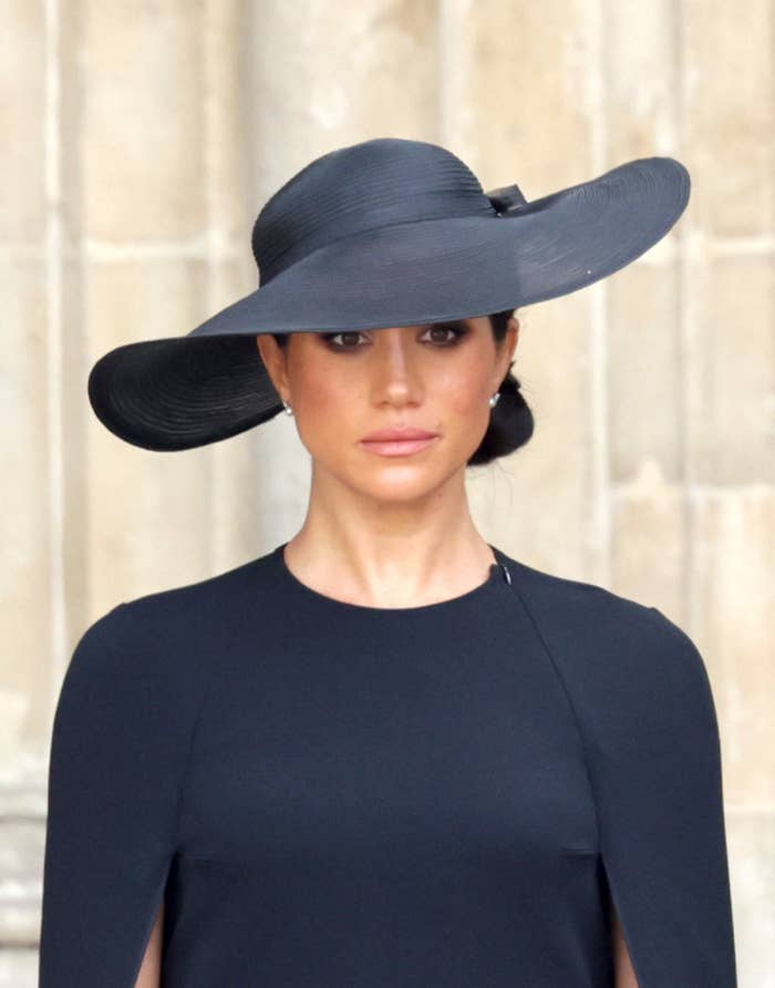 Meghan wearing a cape dress and wide-brimmed hat at Queen Elizabeth&#x27;s funeral