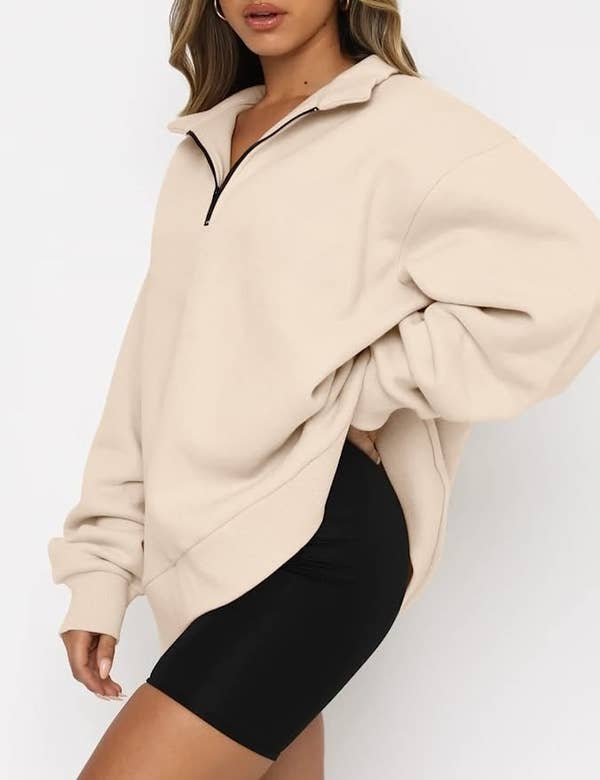 a model wearing the cream colored sweater with black shorts