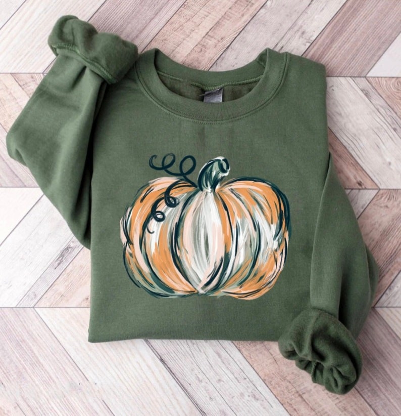 an olive green sweatshirt with a painted pumpkin on it