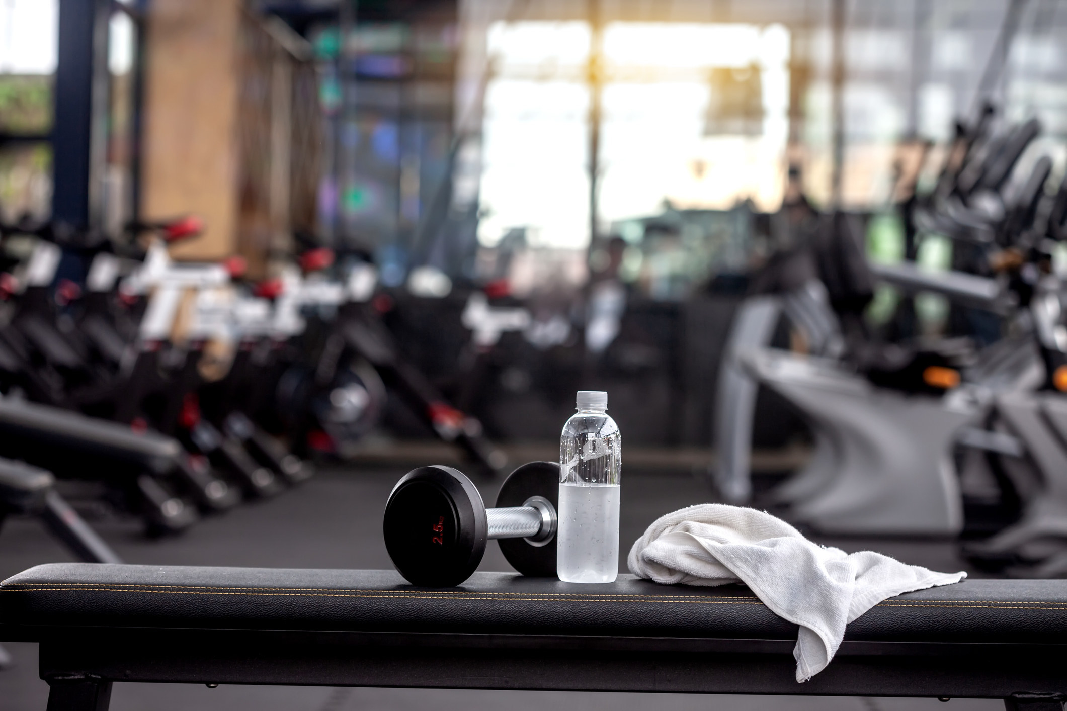 A towel, bottle of water, and weight on a gym bench