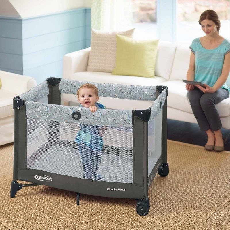 A person watches their baby in the playpen