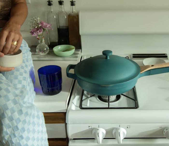 a person sitting next to the stove with a pan on it