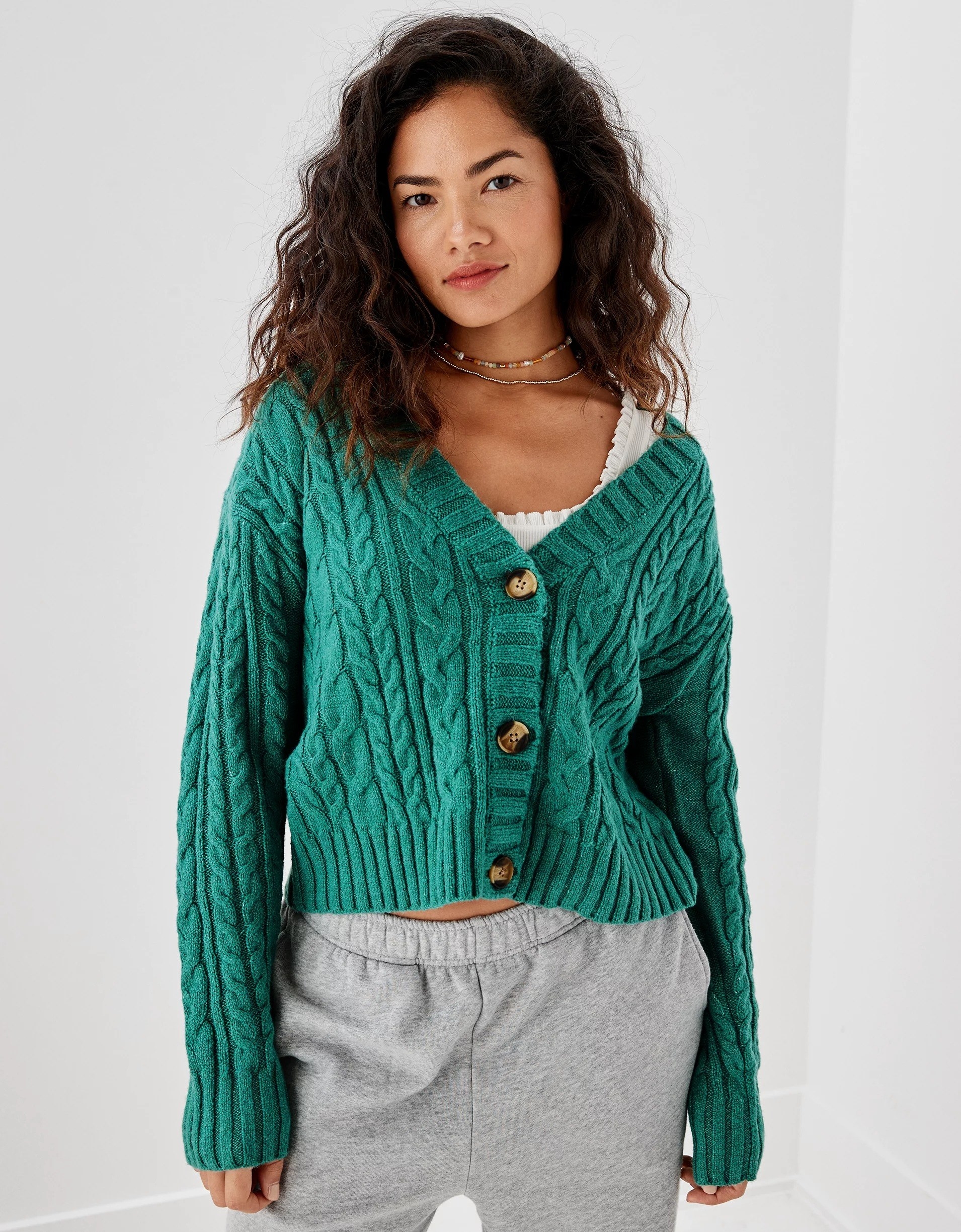 model wearing the cropped green cable knit cardigan with sweatpants