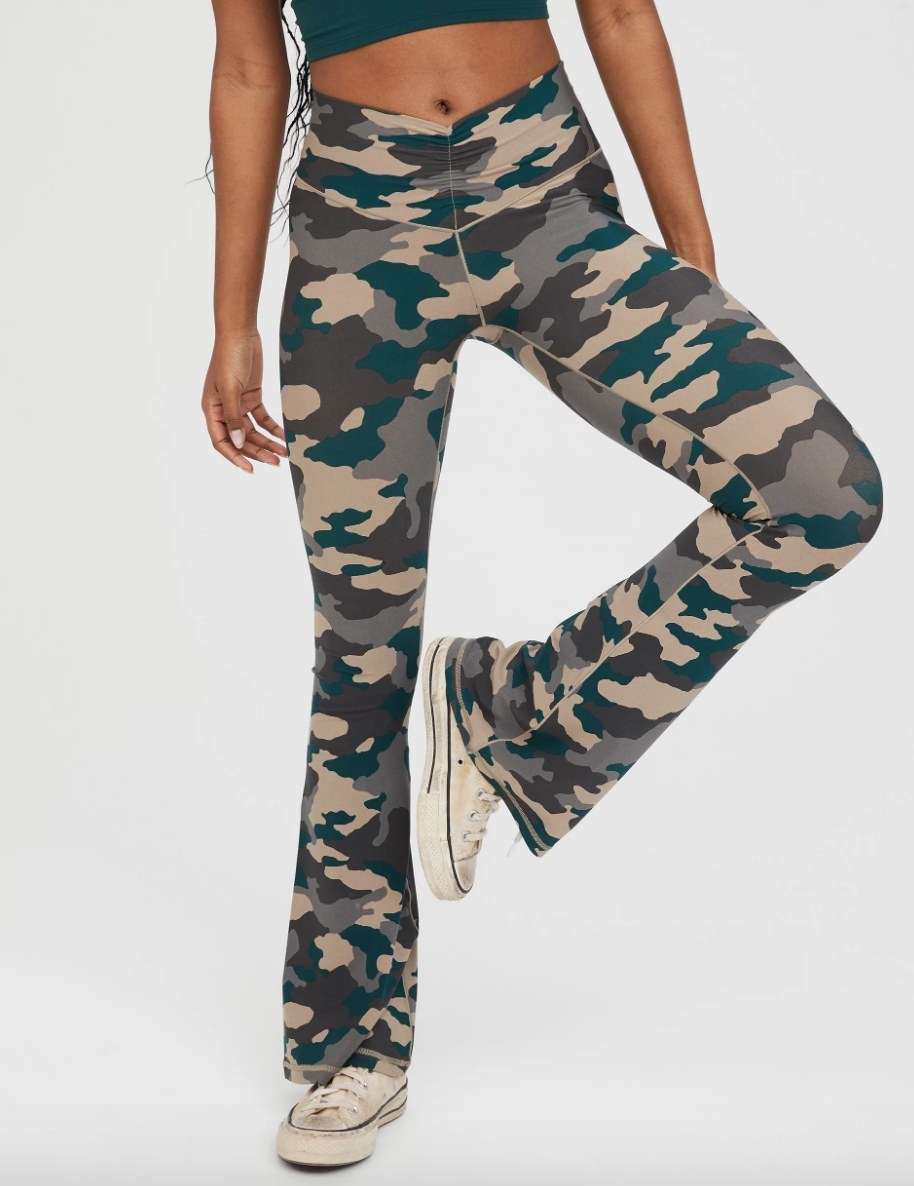 Model wearing green and brown camouflage print flare leggings