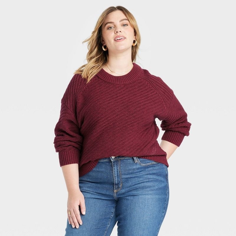 model wearing the crewneck pullover in burgundy with blue jeans
