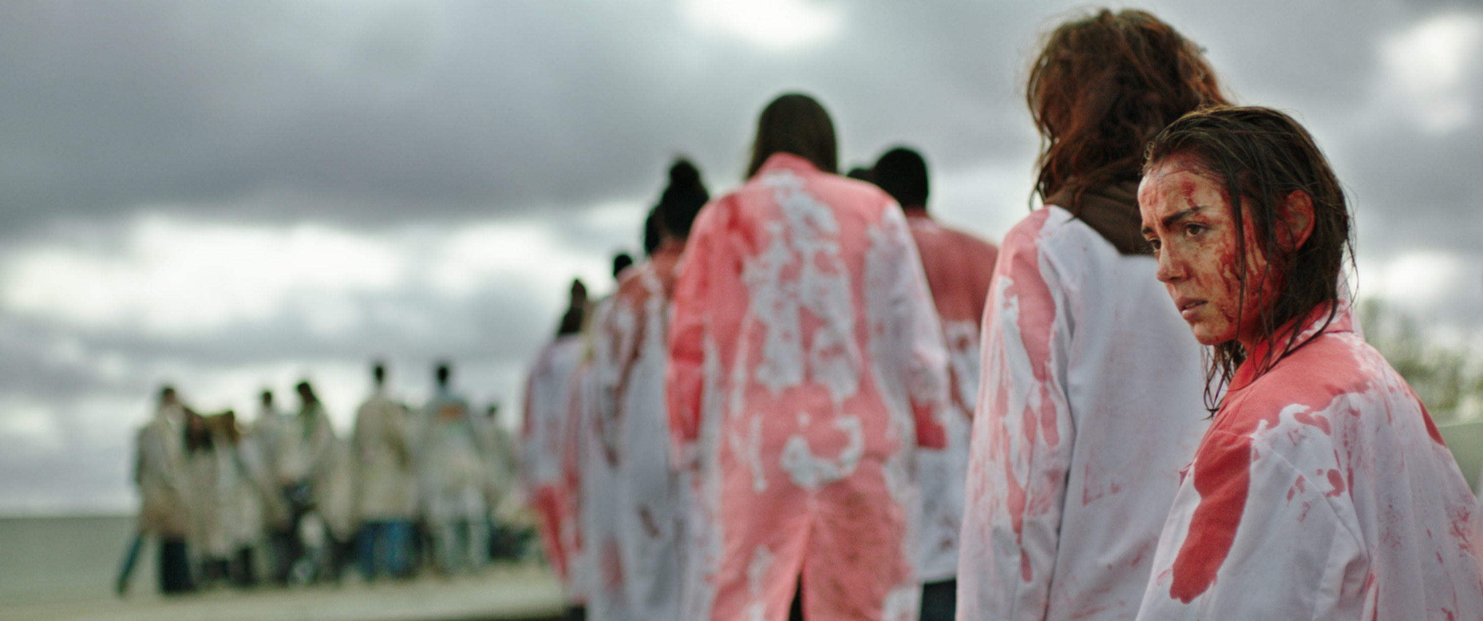 A line of people with bloodied white coats and faces