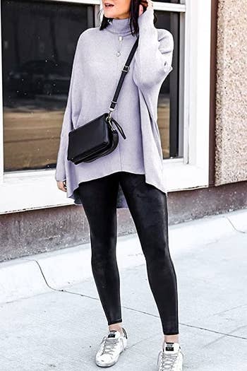 model wearing the long asymmetrical sweater in lavender over black leggings