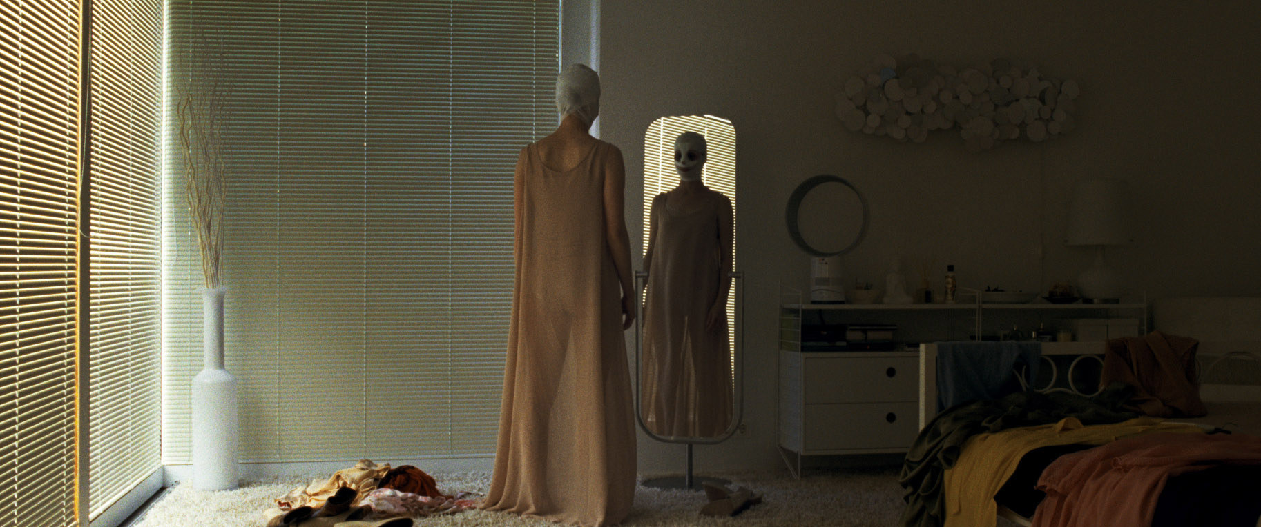 A woman in a mask stands in front of a mirror