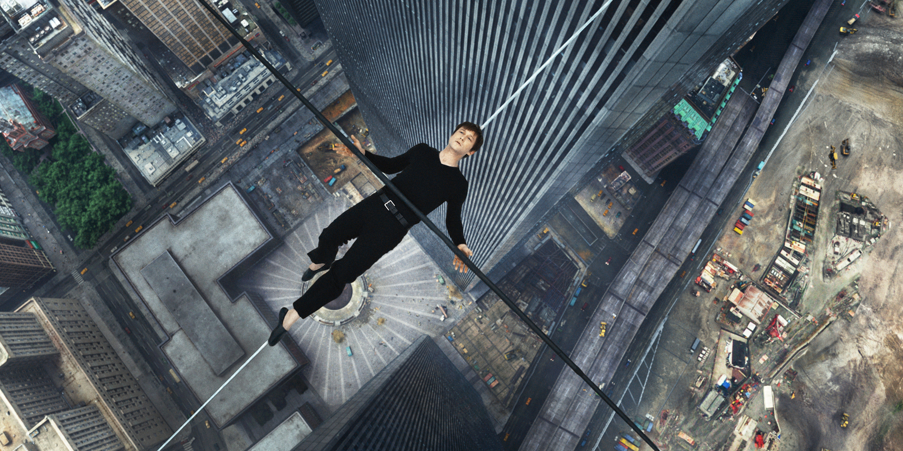 A man lies down on a tight rope above a city