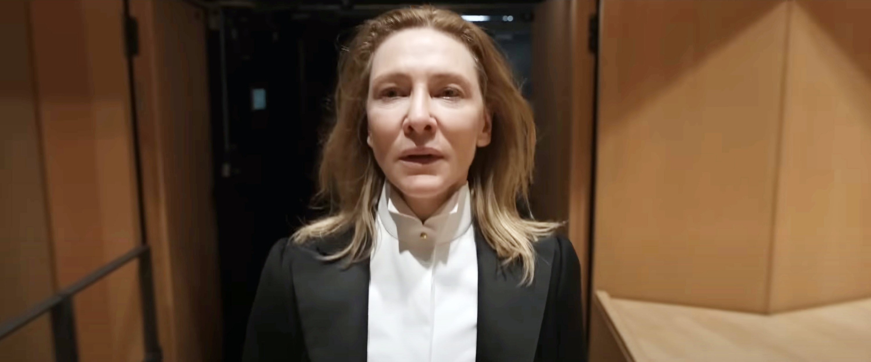 Cate Blanchette stands in a tux backstage