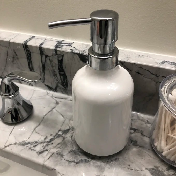 A white soap dispenser sitting on a countertop