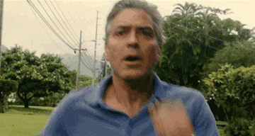 George Clooney running outside in a blue polo