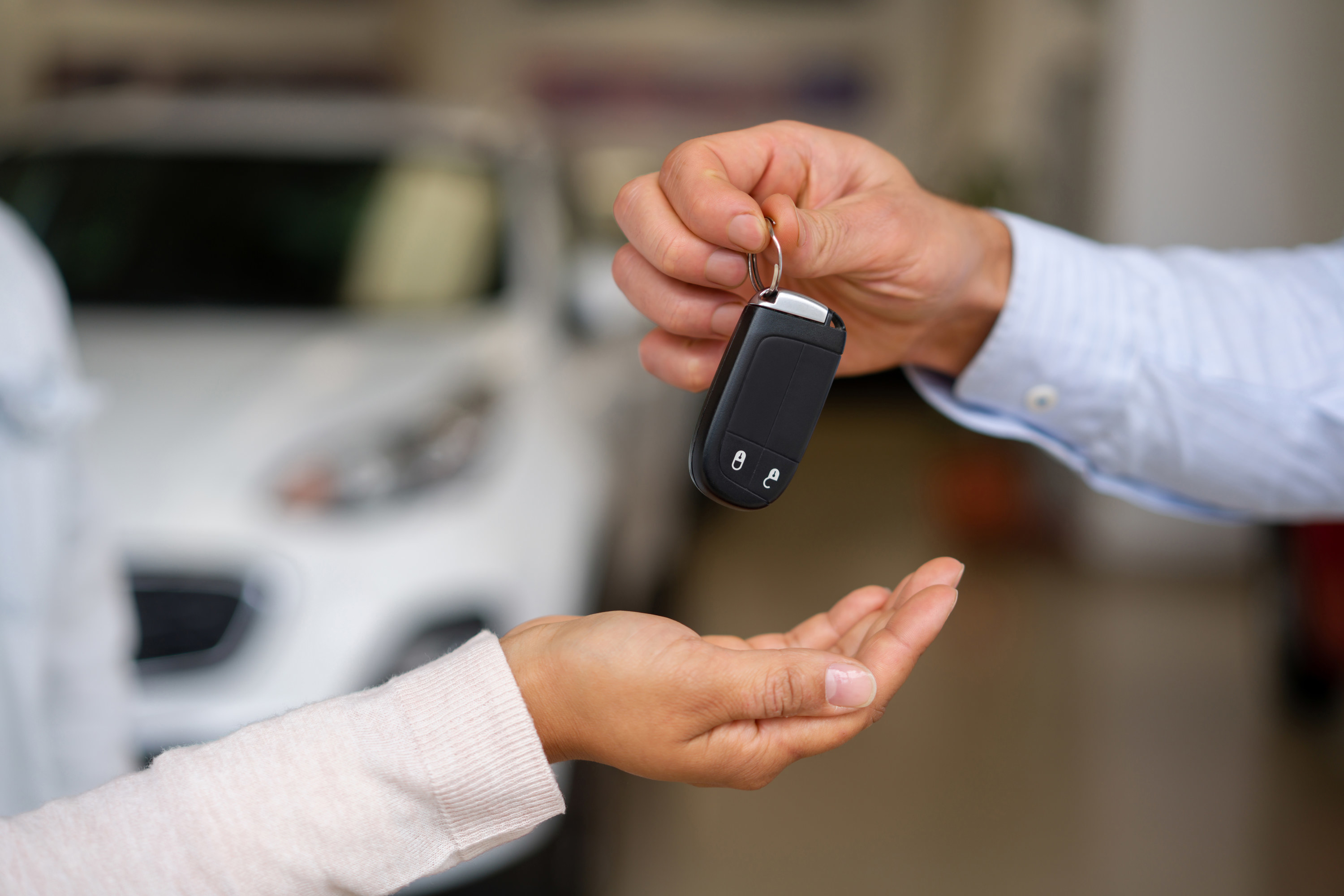 man handing a woman the keys to a rental car