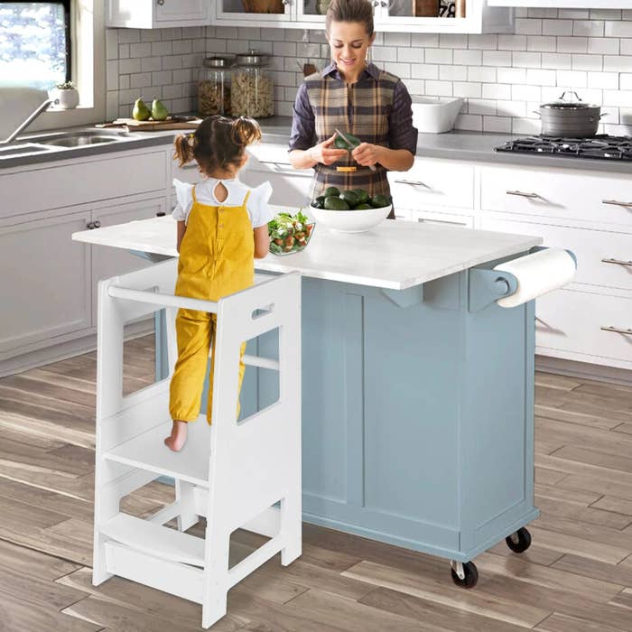 Little girl on white step stool in kitchen