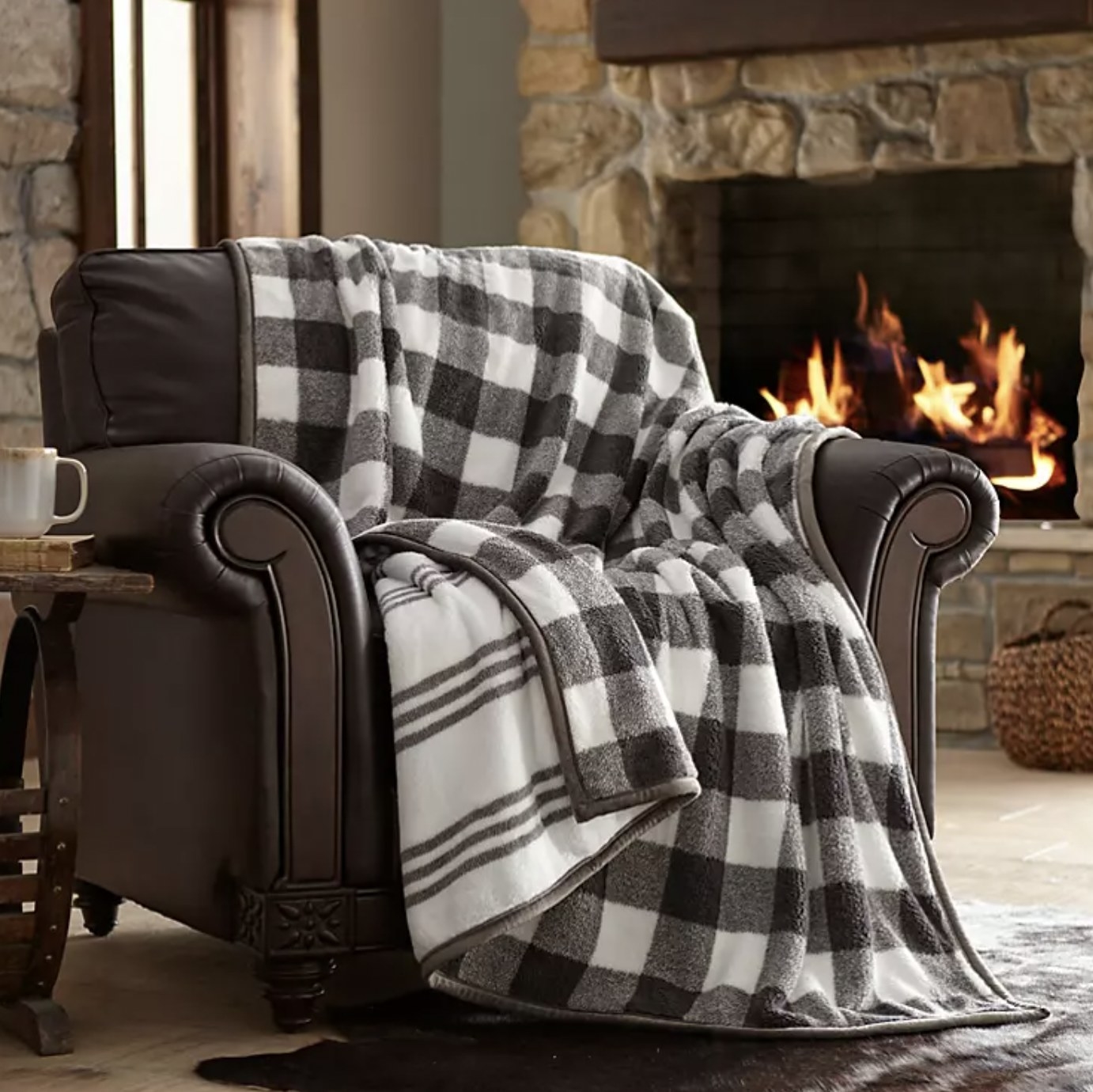The grey and white throw draped over armchair with plaid pattern on one side and stripes on the other