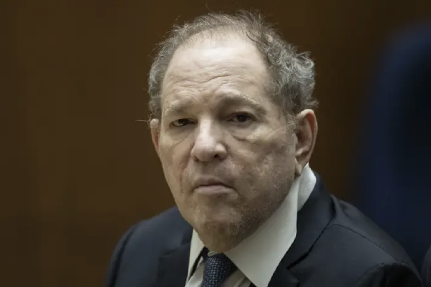 harvey weinstein in a suit grimacing and looking old and weary