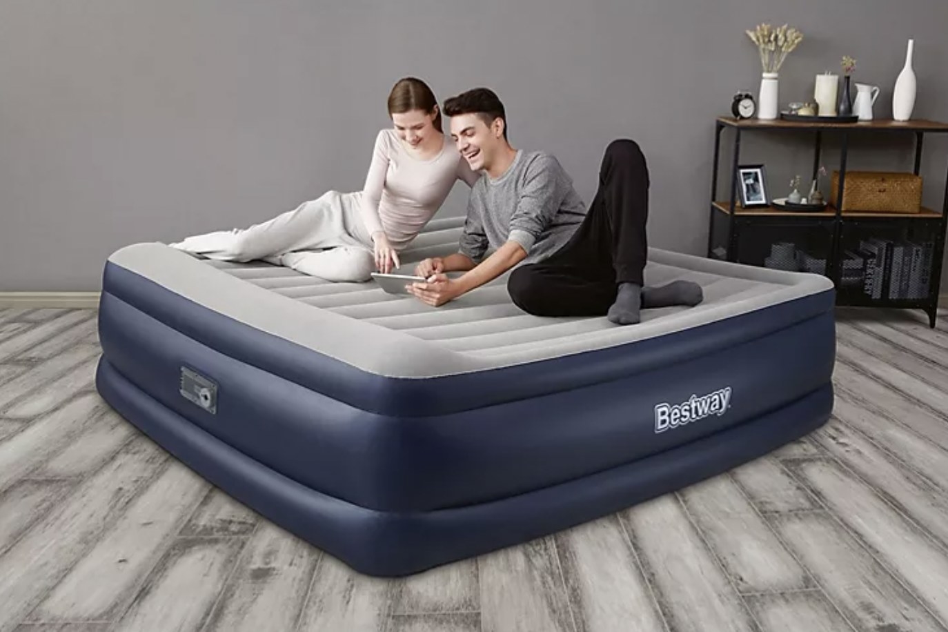 two people lounging on the air mattress playing on a tablet