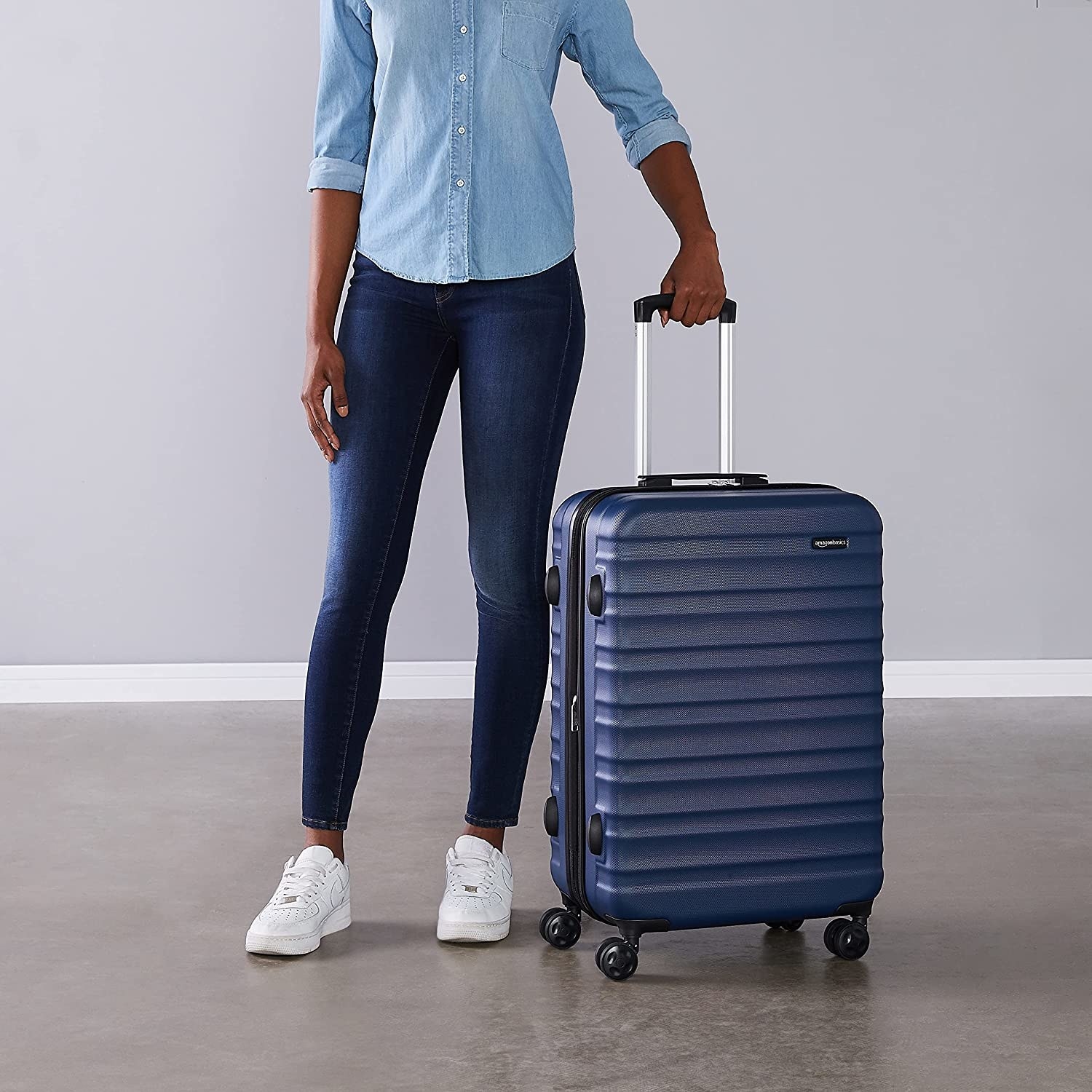 a person holding the handle of the hardshell luggage