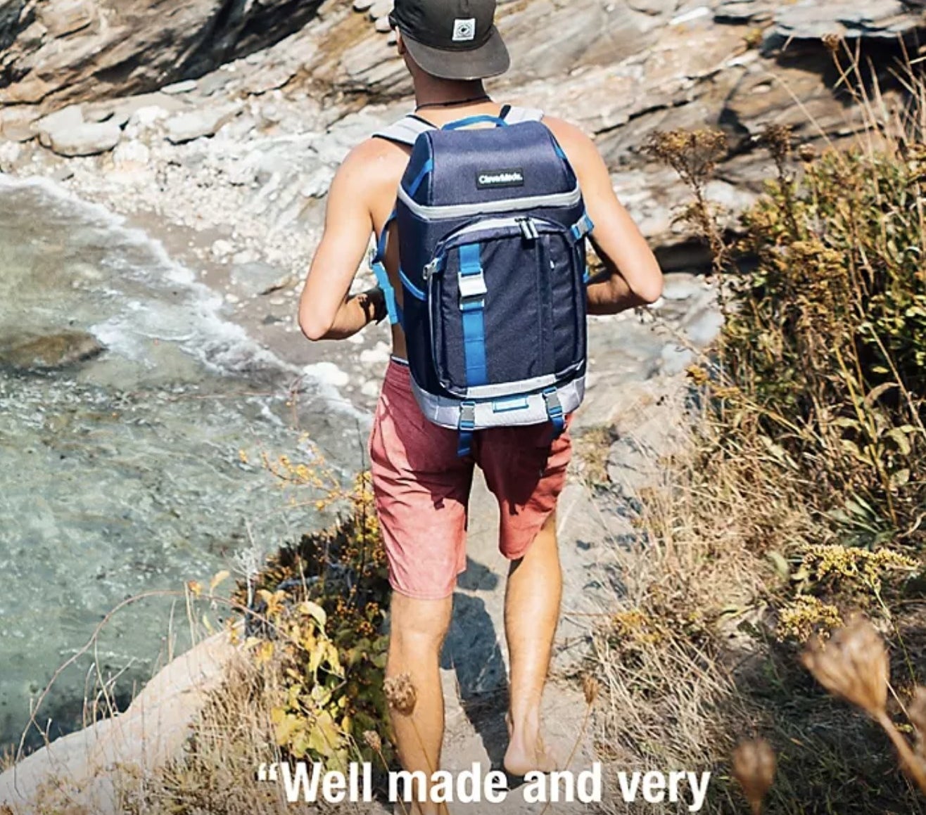 Model walking outdoors by beach with blue backpack. Caption reads &quot;well made and intelligently designed&quot; –Jeddy