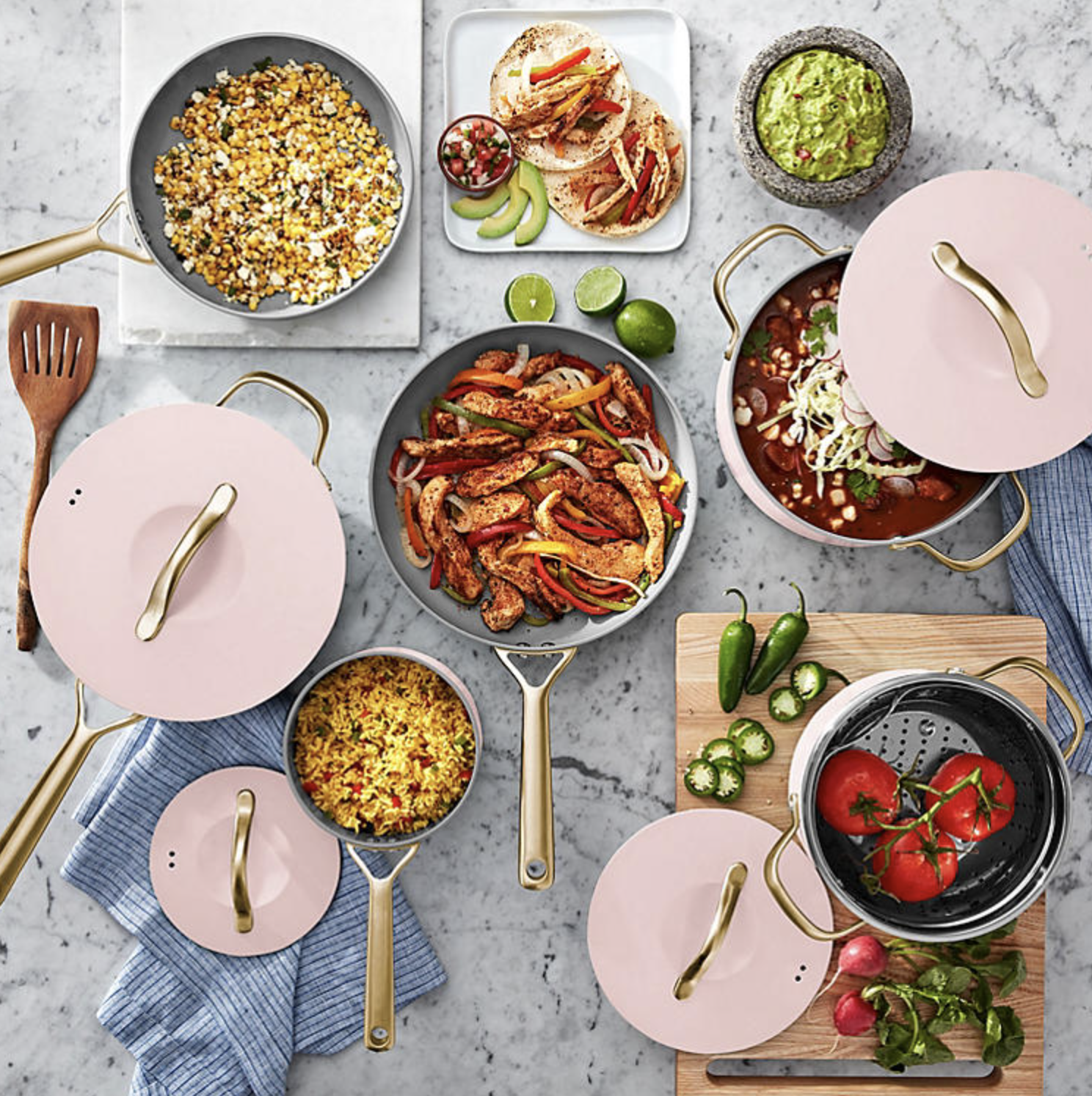 the pink and gold cookware set with food in each pot and pan