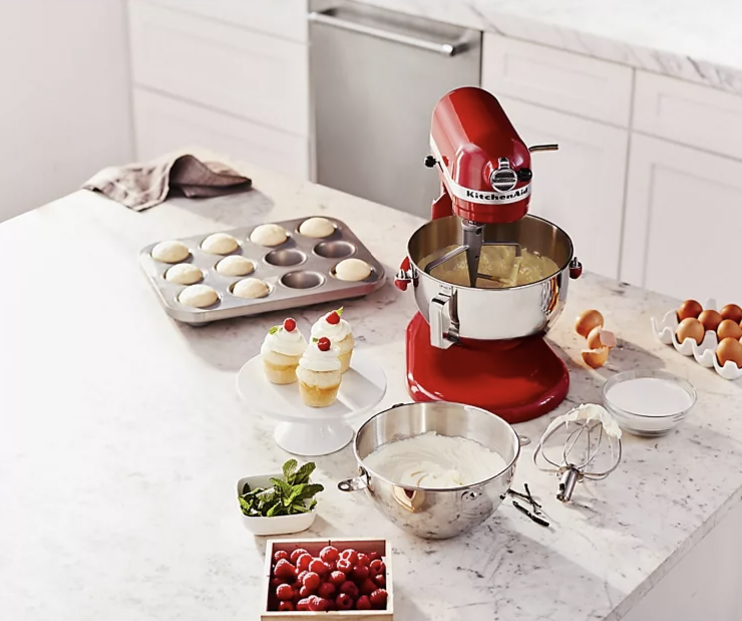 the red mixer on a counter with cupcake ingredients next to it