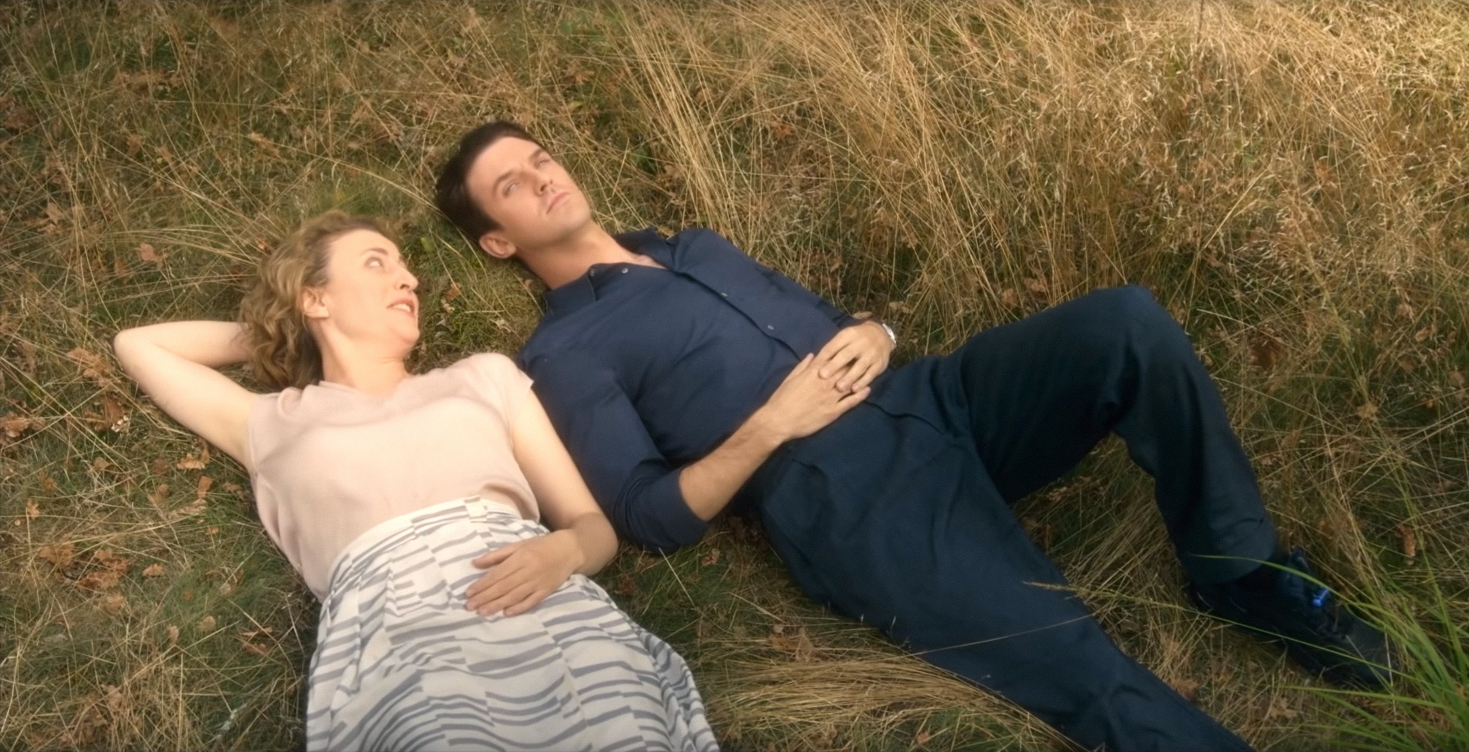 Maren Eggert and Dan Stevens lie in a field