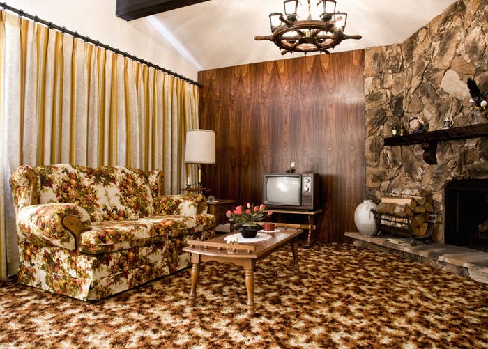 living room with patterned carpet, floral couch and wood panel wall