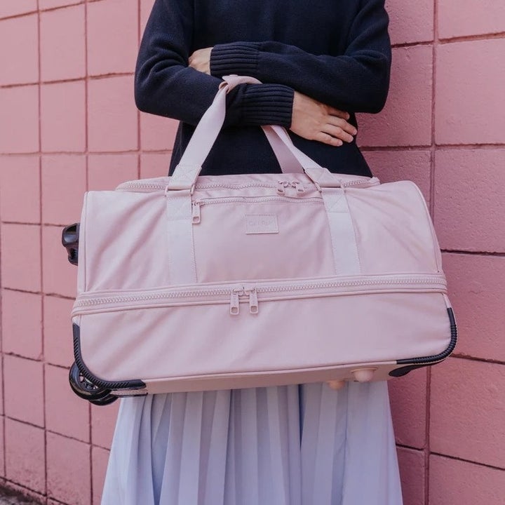 model holding a rolling duffel bag