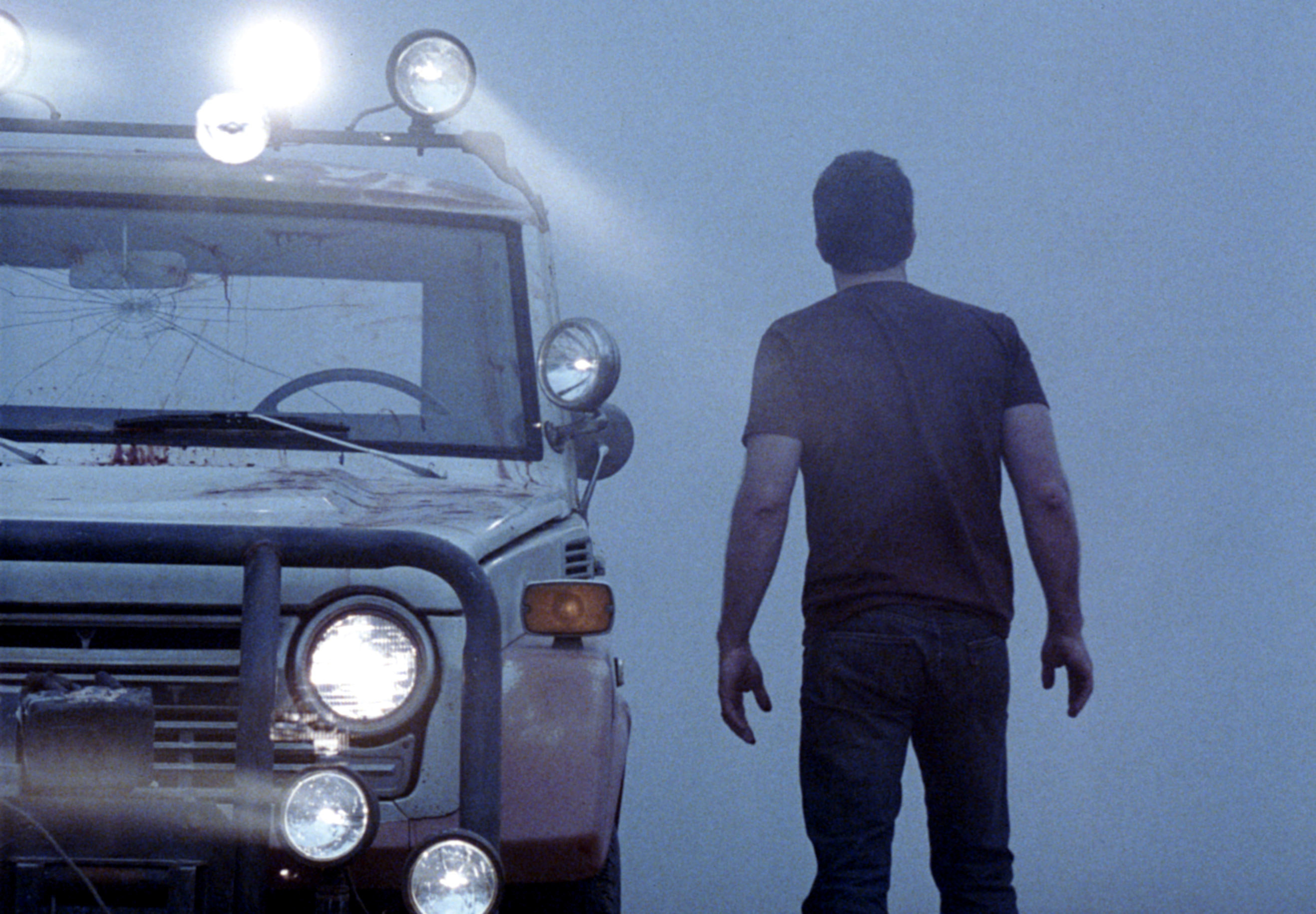 A man approaches a car in the mist
